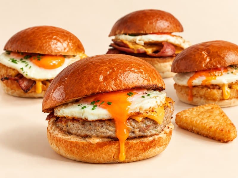 Breakfast brioche buns with sausage, fried egg and a hash brown